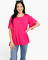 A woman modeling a bright pink short-sleeve top with layered ruffle details on the sleeves, paired with blue jeans, against a plain white studio background.