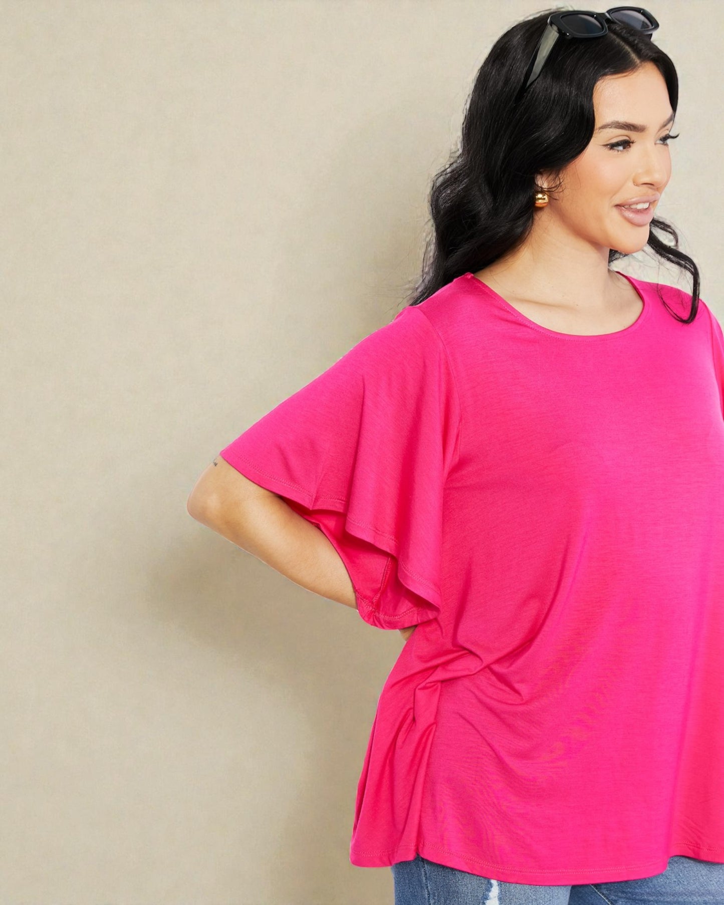 Woman wearing a bright pink top against a beige background