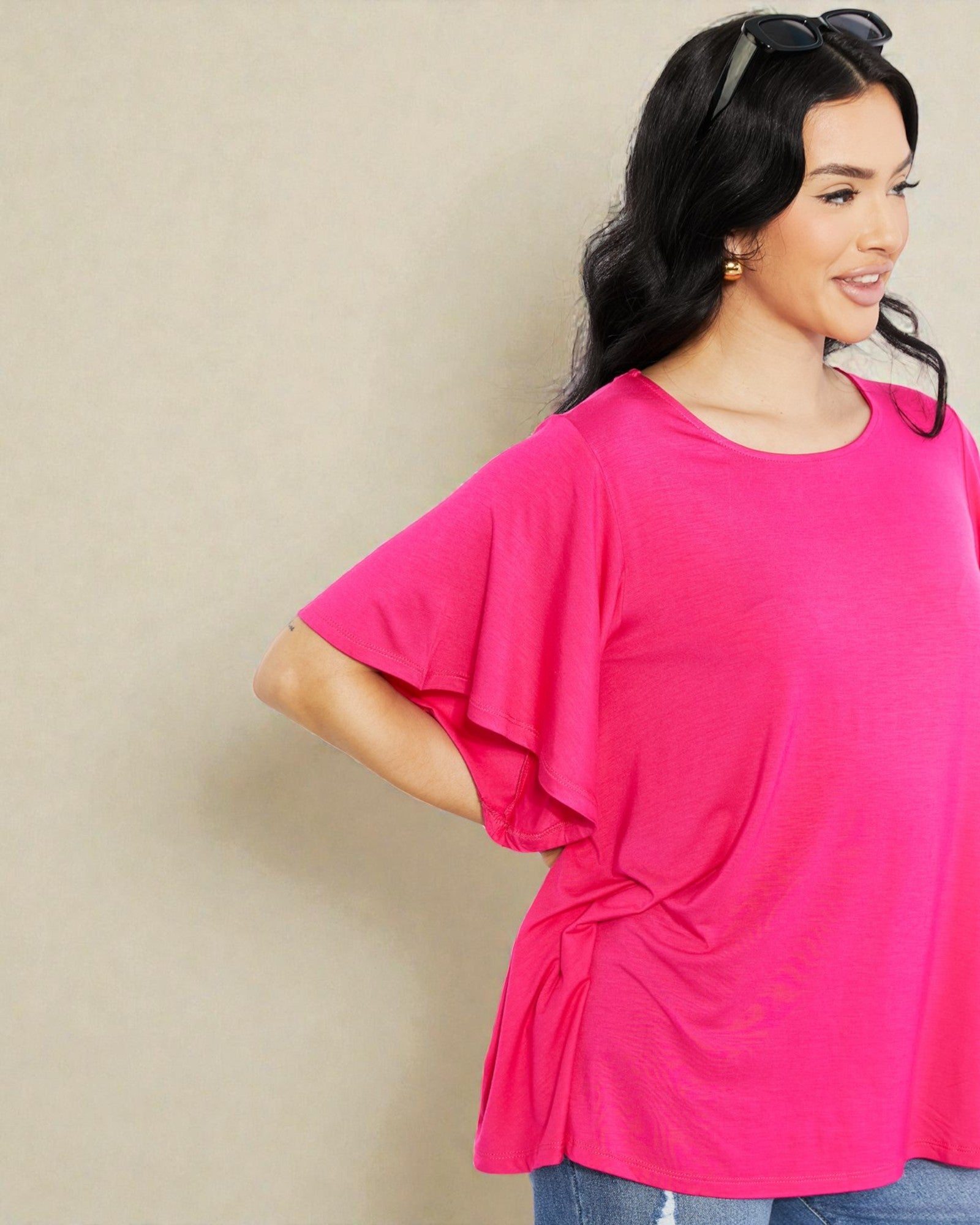 Woman wearing a bright pink top against a beige background