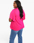 A woman wearing a bright pink short-sleeve top with flutter sleeves and pleated detailing at the hem, paired with blue jeans, shown from a three-quarters back view against a plain white background.