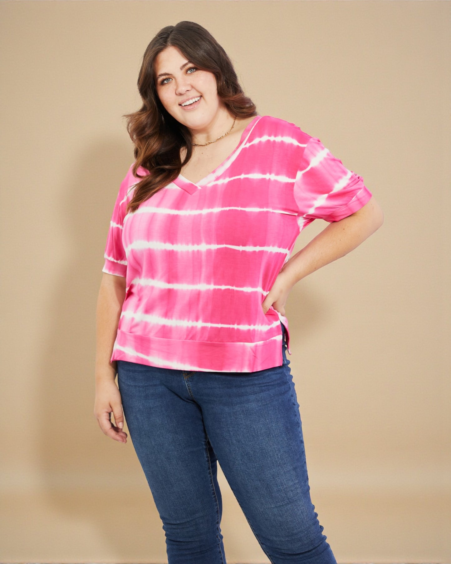 Woman wearing a pink and white striped shirt and blue jeans on a beige background
