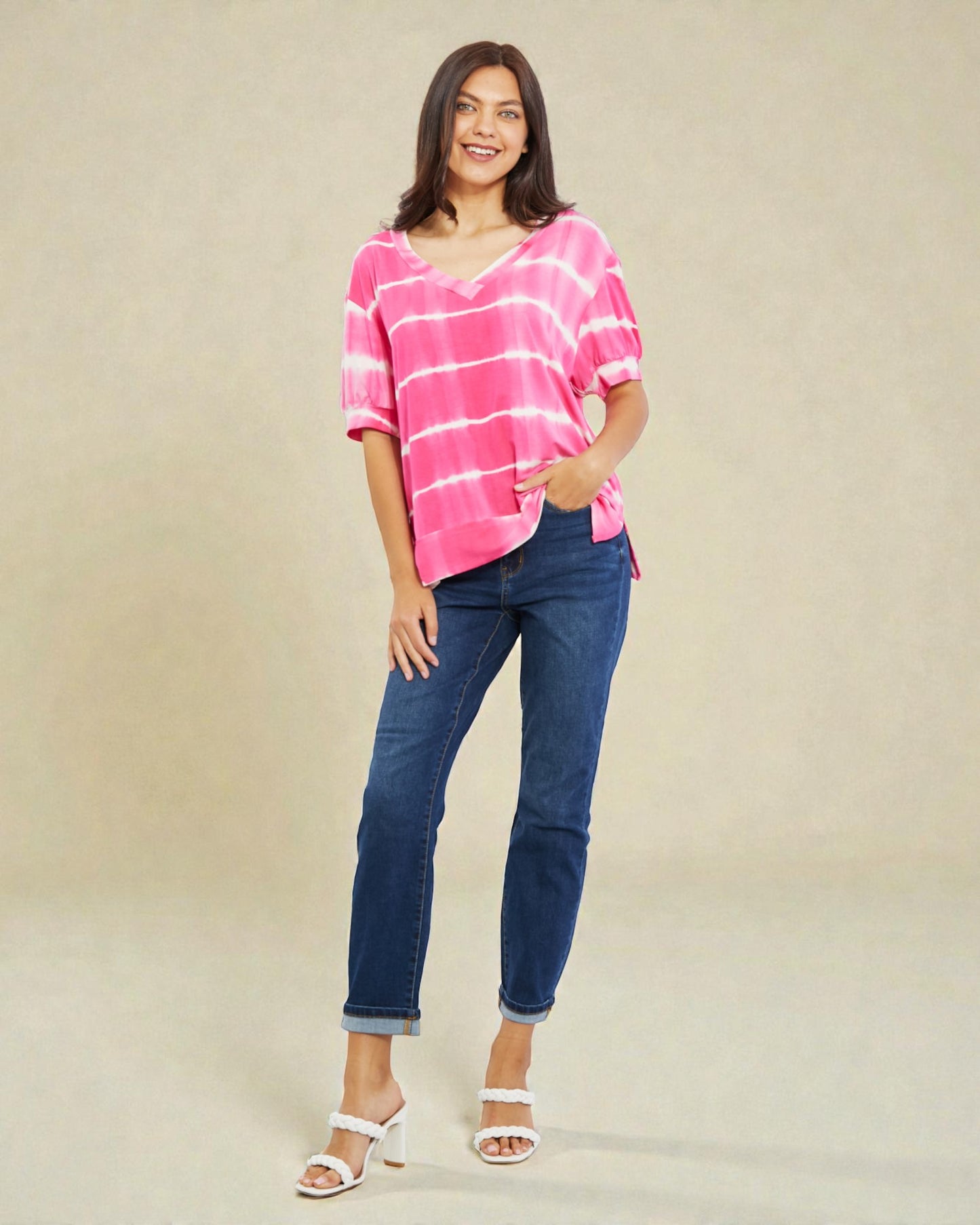 Woman wearing a pink striped shirt and blue jeans on a beige background