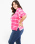 A woman modeling a pink and white tie-dye short-sleeve top with blue jeans against a plain white background.