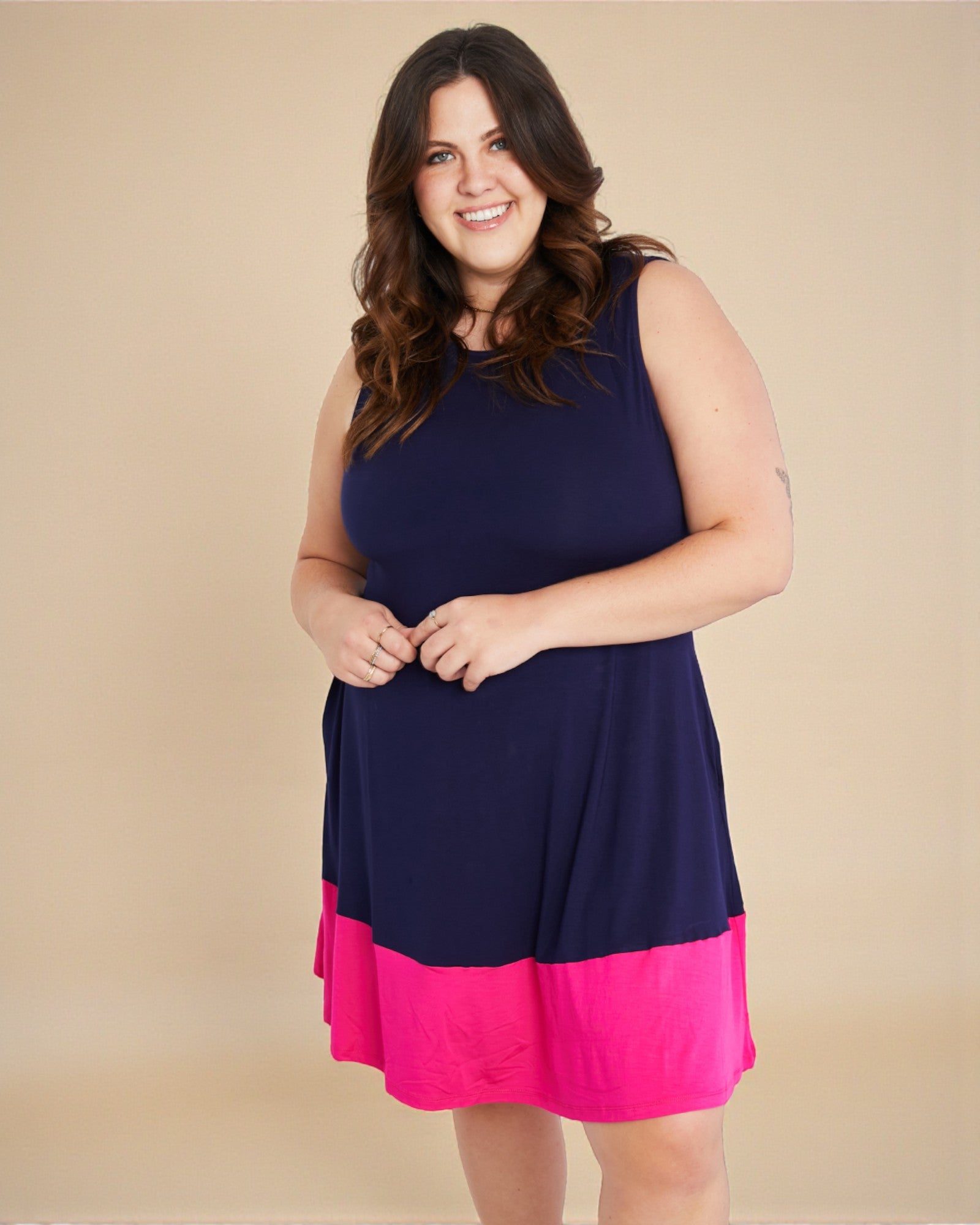 Woman wearing a navy blue and pink dress against a beige background