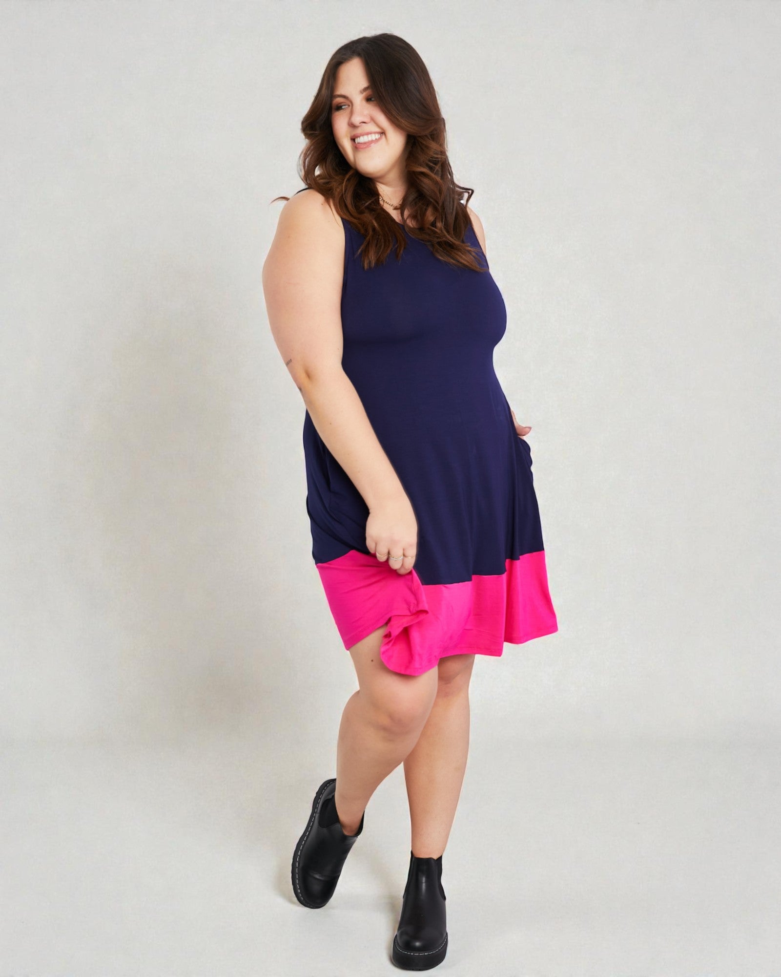 Woman wearing a navy dress with pink bottom half on a white background
