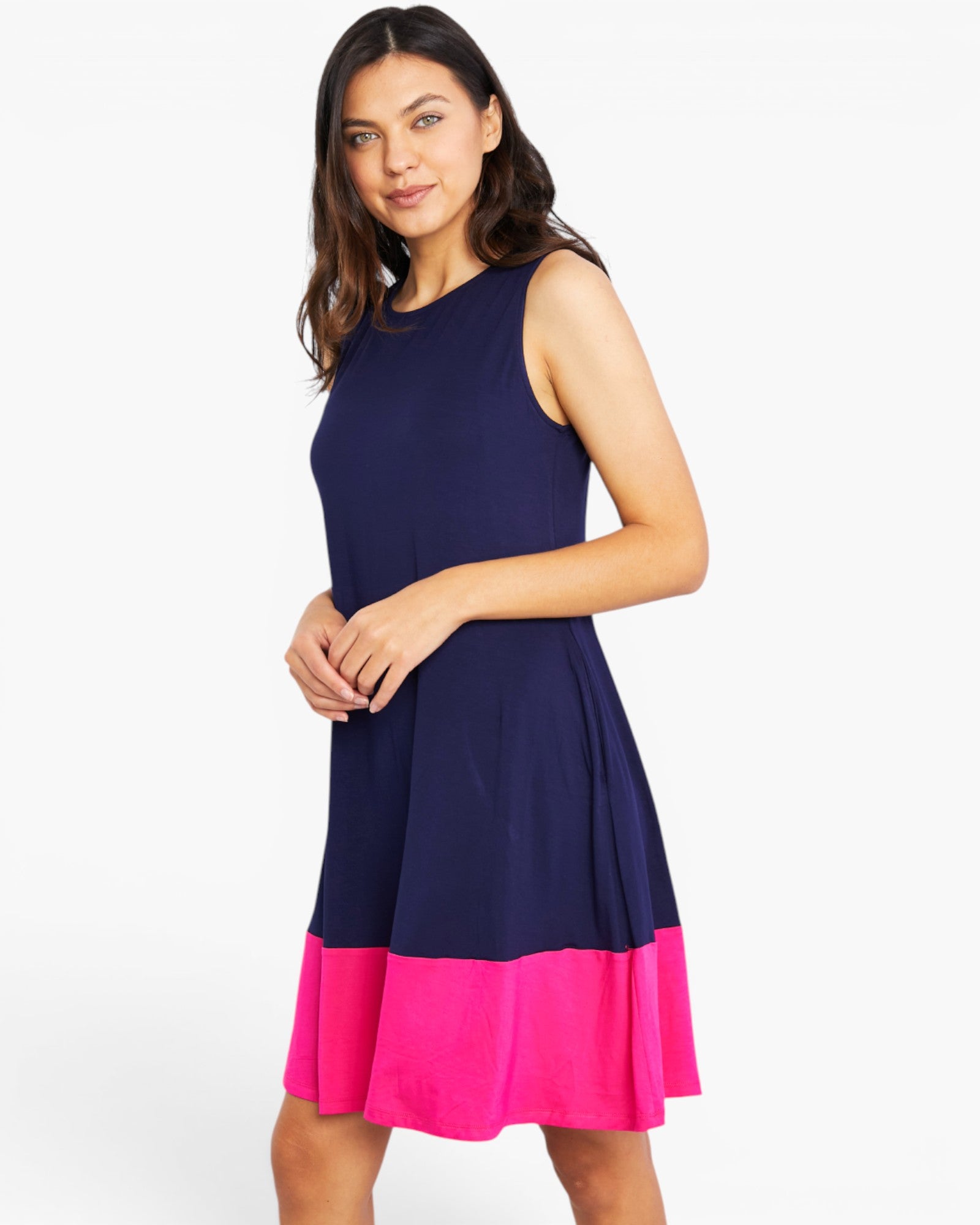 A woman modeling a sleeveless colorblock dress with a navy blue upper section and a bright pink flared hem, set against a plain white studio background.