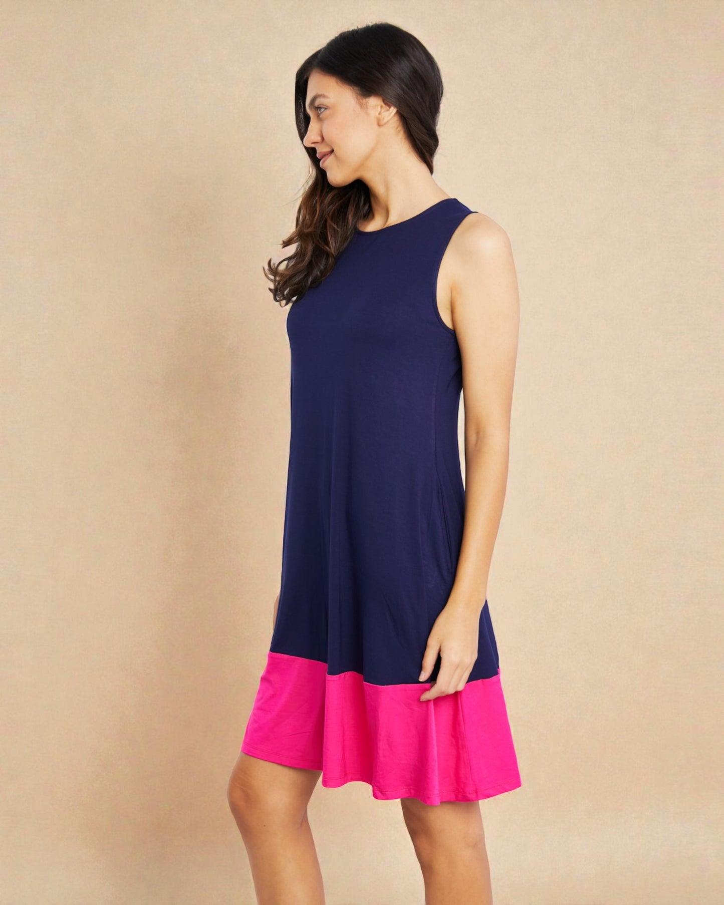 Woman wearing a navy blue and pink dress against a beige background