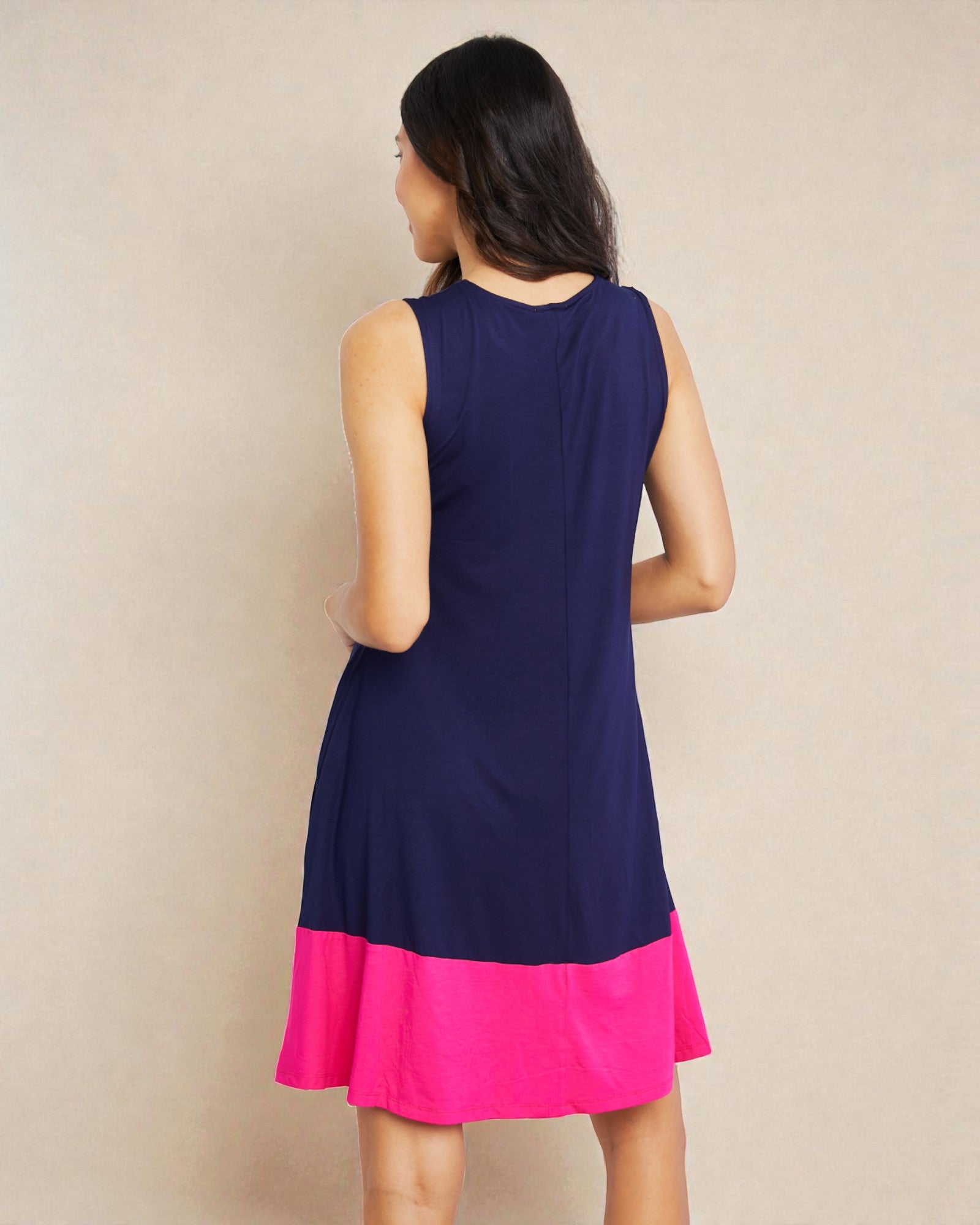 Woman wearing a navy blue and pink dress against a beige background