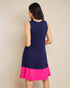 Woman wearing a navy blue and pink dress against a beige background