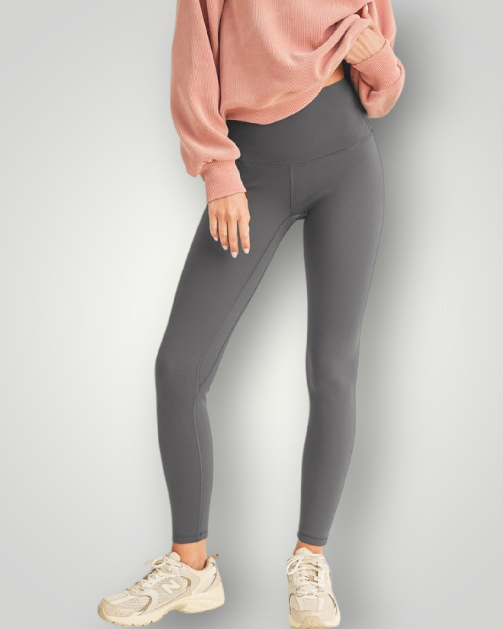 Person wearing gray leggings and a pink sweatshirt on a light gray background