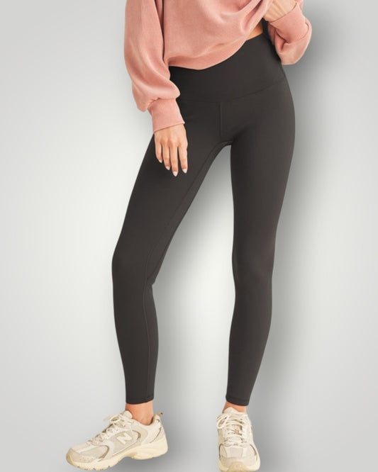 Person wearing black leggings and a pink sweatshirt on a light gray background