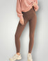 Person wearing brown leggings and a pink sweatshirt on a light gray background