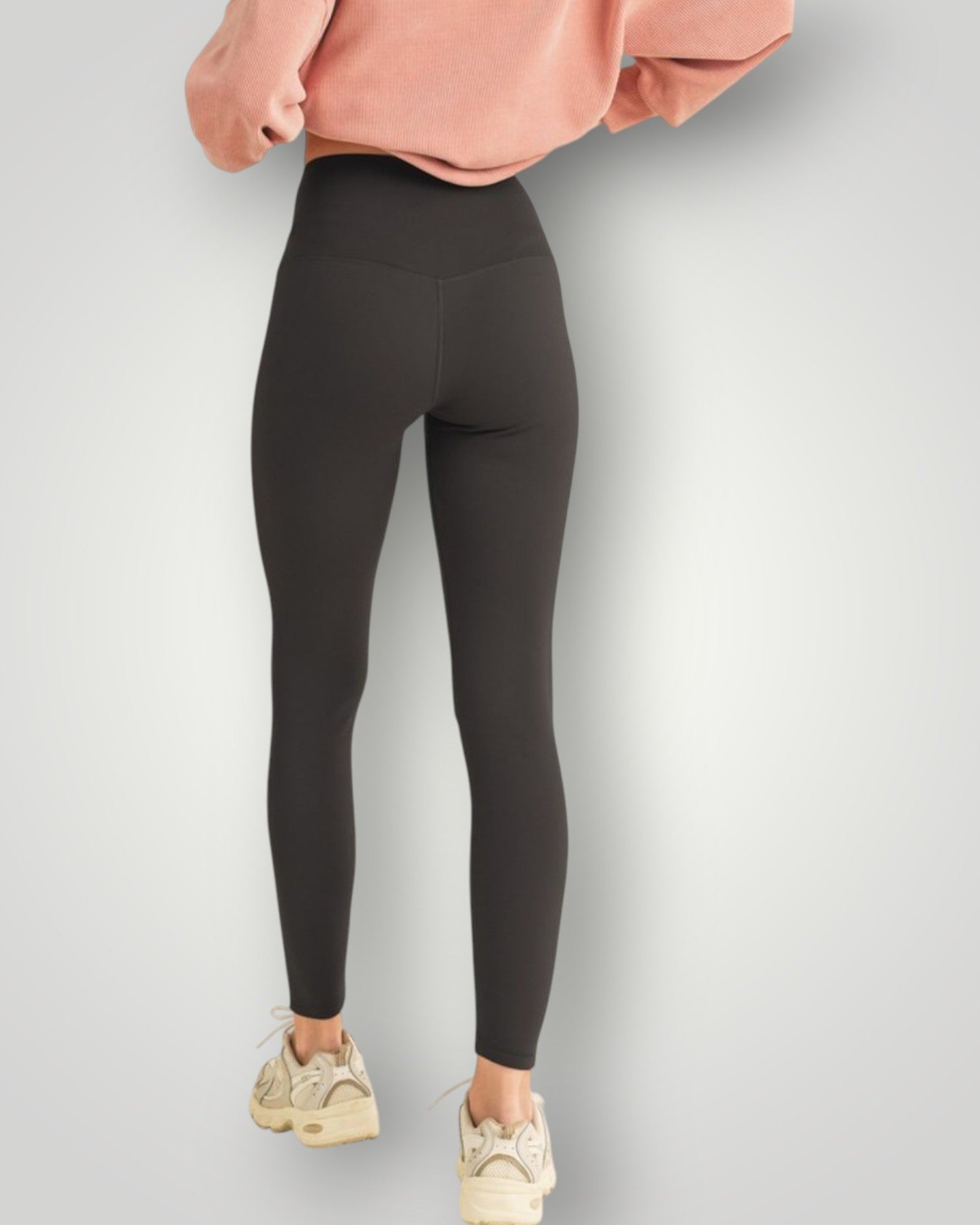 Person wearing black leggings and a pink sweatshirt on a light gray background