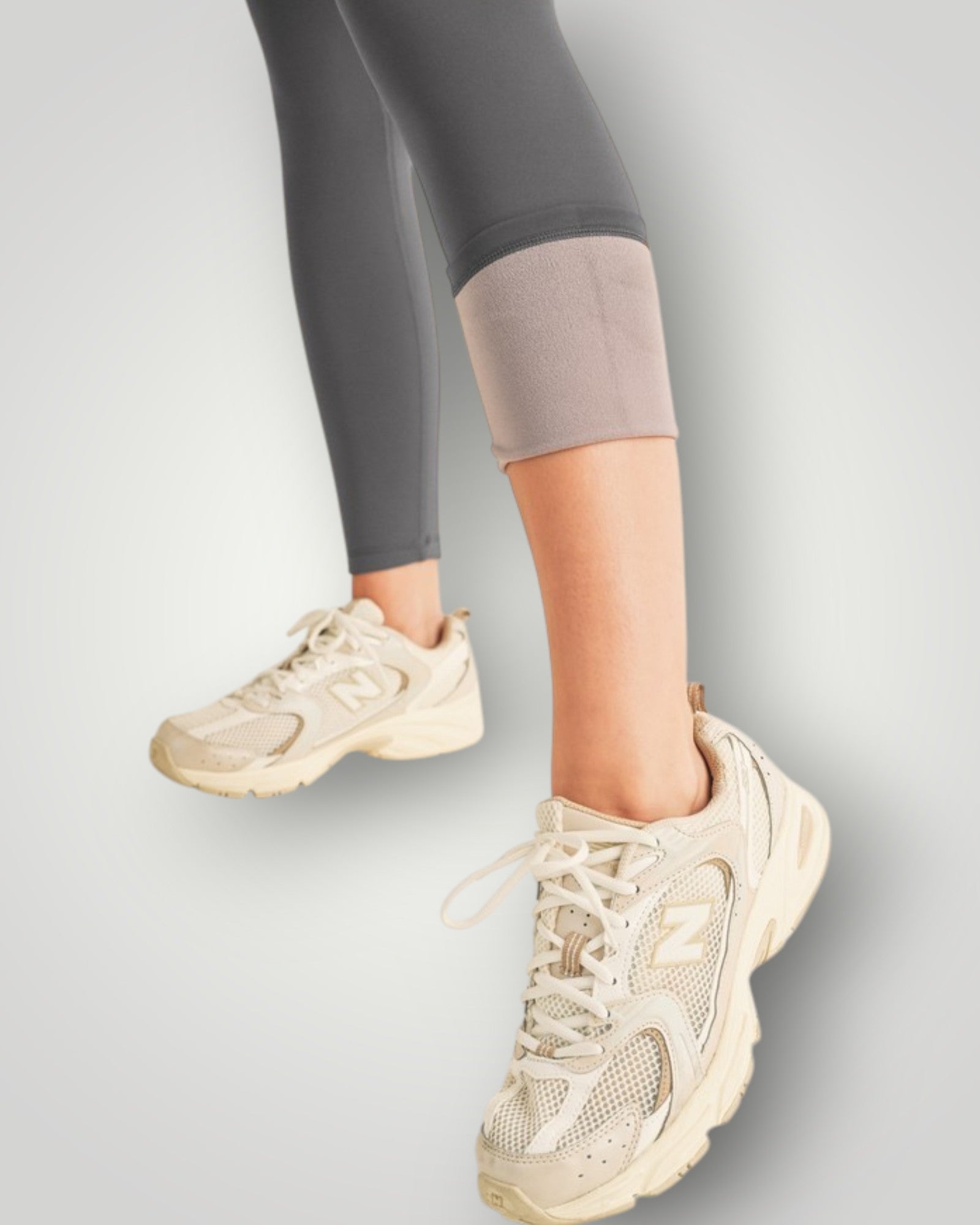 Beige sneakers worn with gray leggings on a light gray background