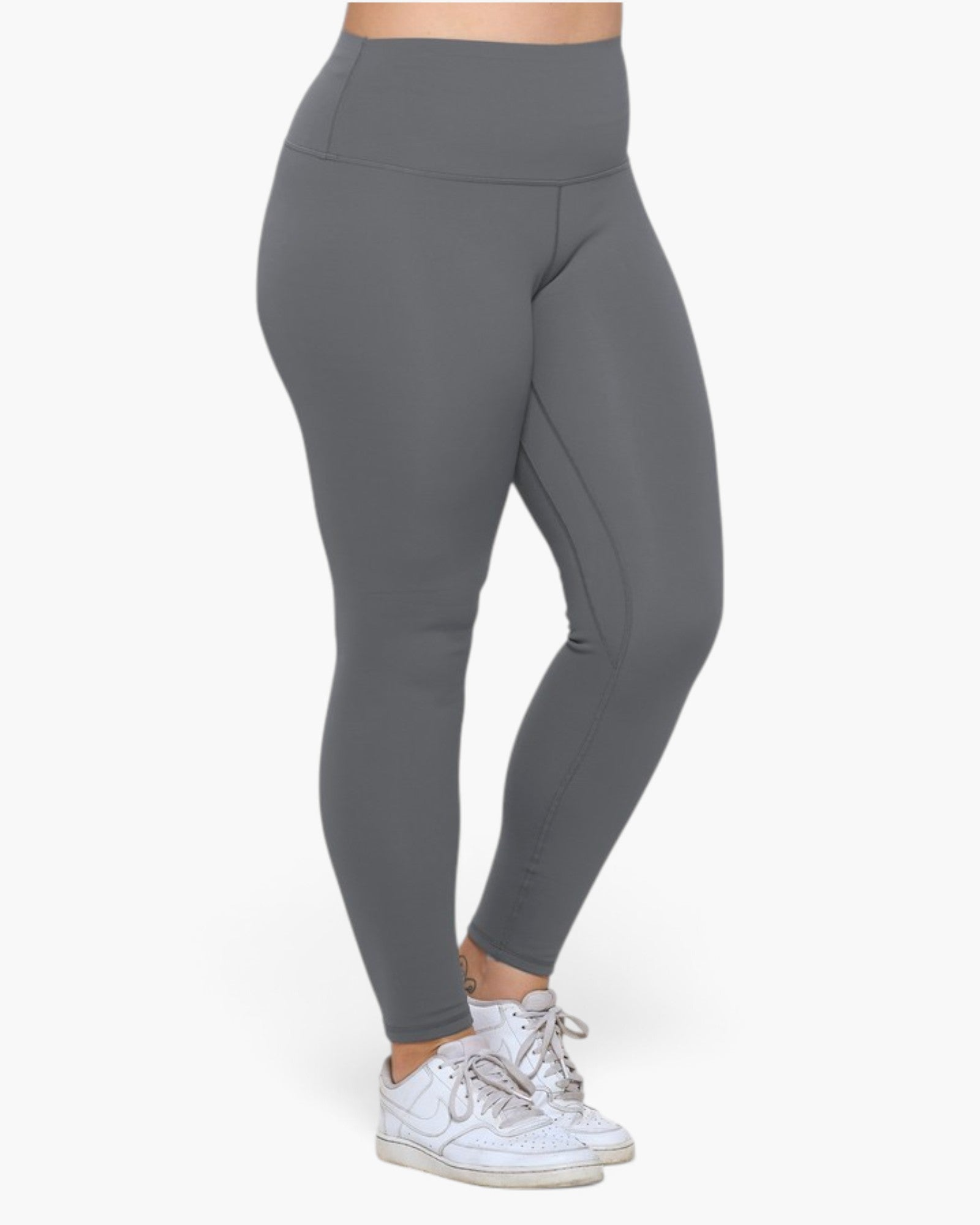 A person wearing high-waisted, full-length gray leggings and white sneakers, shown from the waist down against a plain light background.