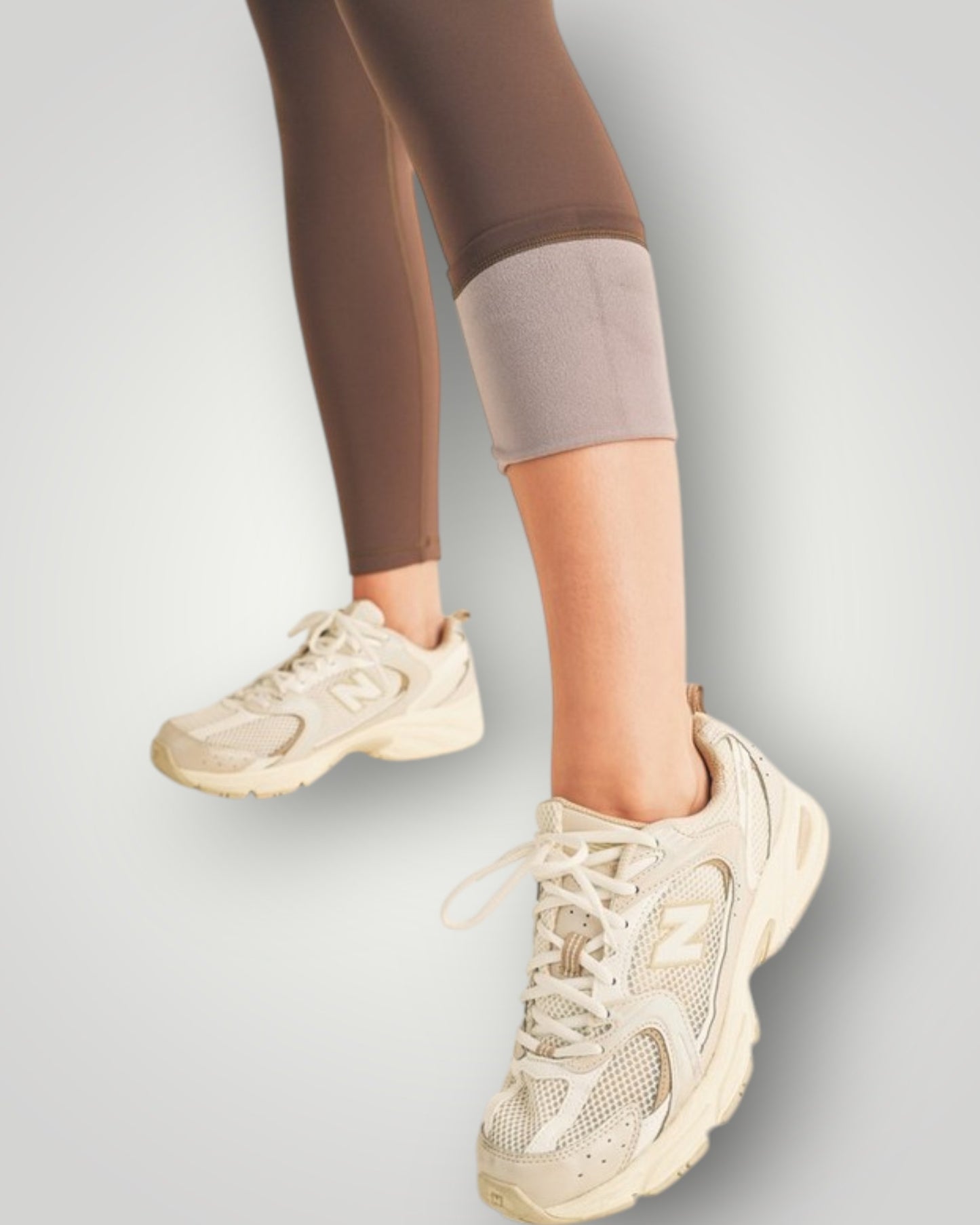 Beige sneakers worn with brown leggings on a light gray background
