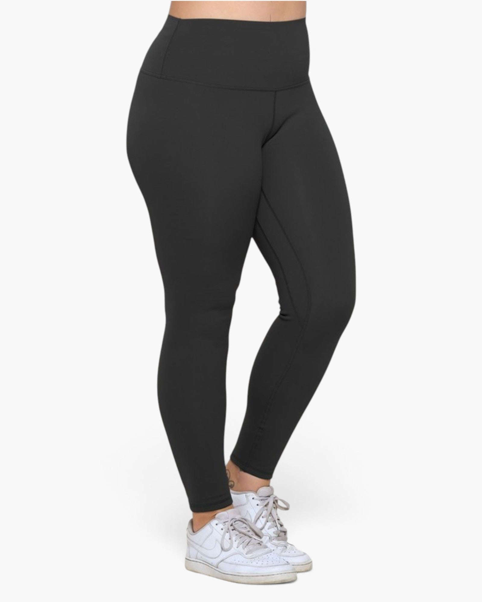 A person wearing black high-waisted leggings and white sneakers, shown from the waist down against a plain light background.