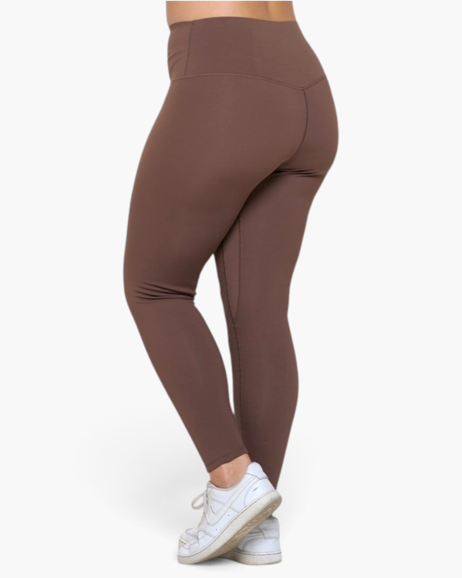A person wearing high-waisted, form-fitting leggings in a solid taupe-brown color, shown from a side-rear angle against a clean white background.