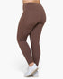 A person wearing high-waisted, form-fitting leggings in a solid taupe-brown color, shown from a side-rear angle against a clean white background.