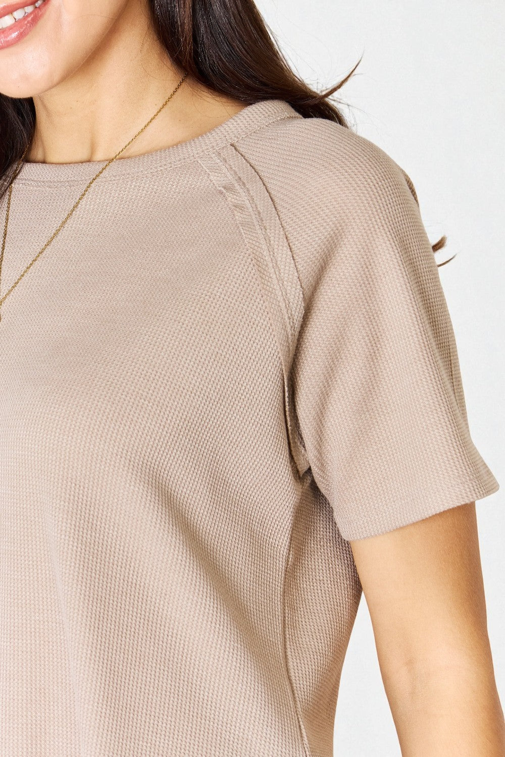 Close-up of a person wearing a beige short-sleeve shirt on a white background