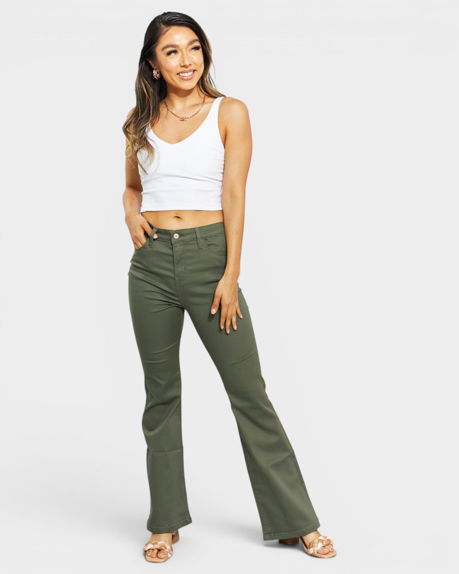 Woman wearing green pants and a white top on a white background