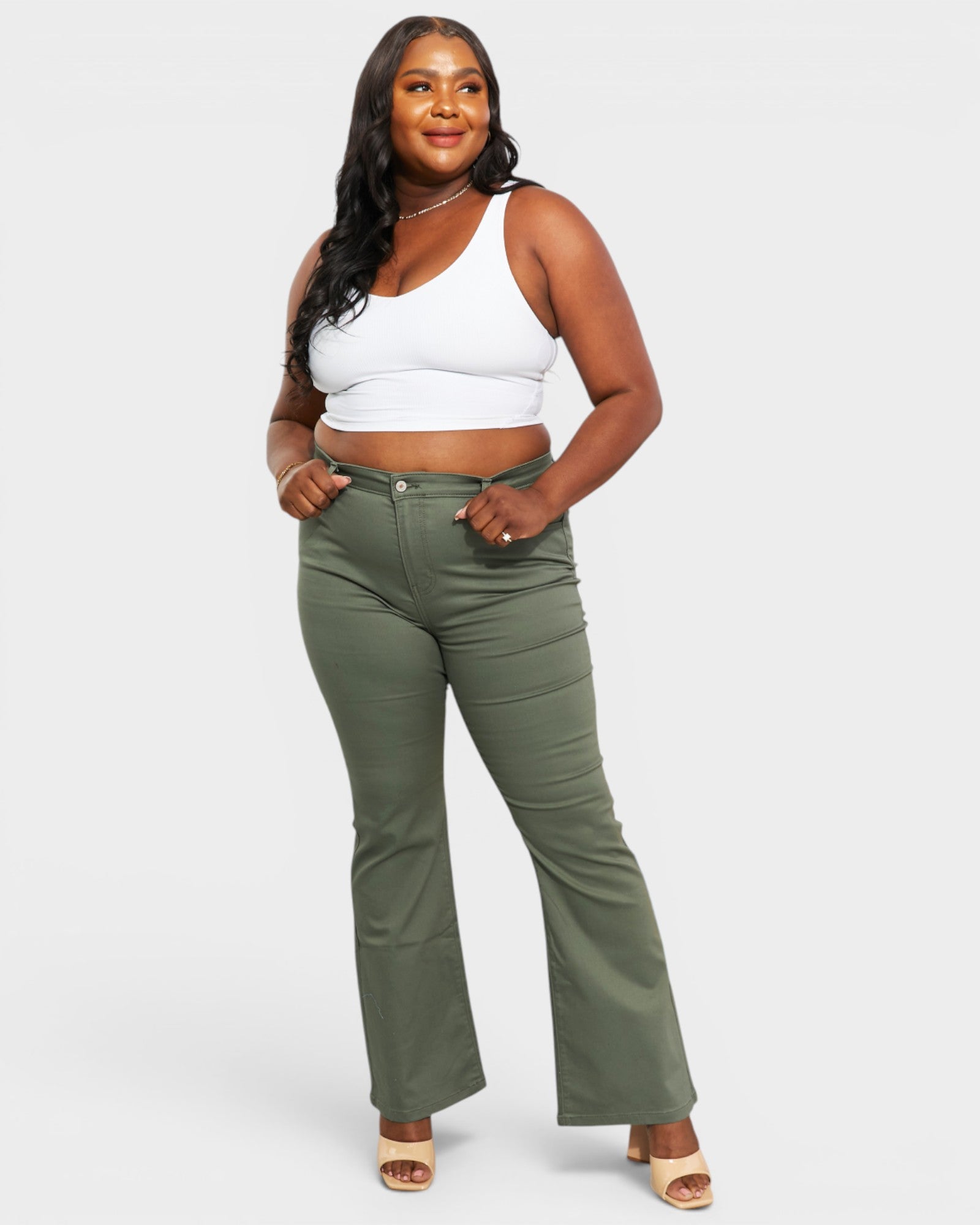 Woman wearing a white crop top and green pants on a white background