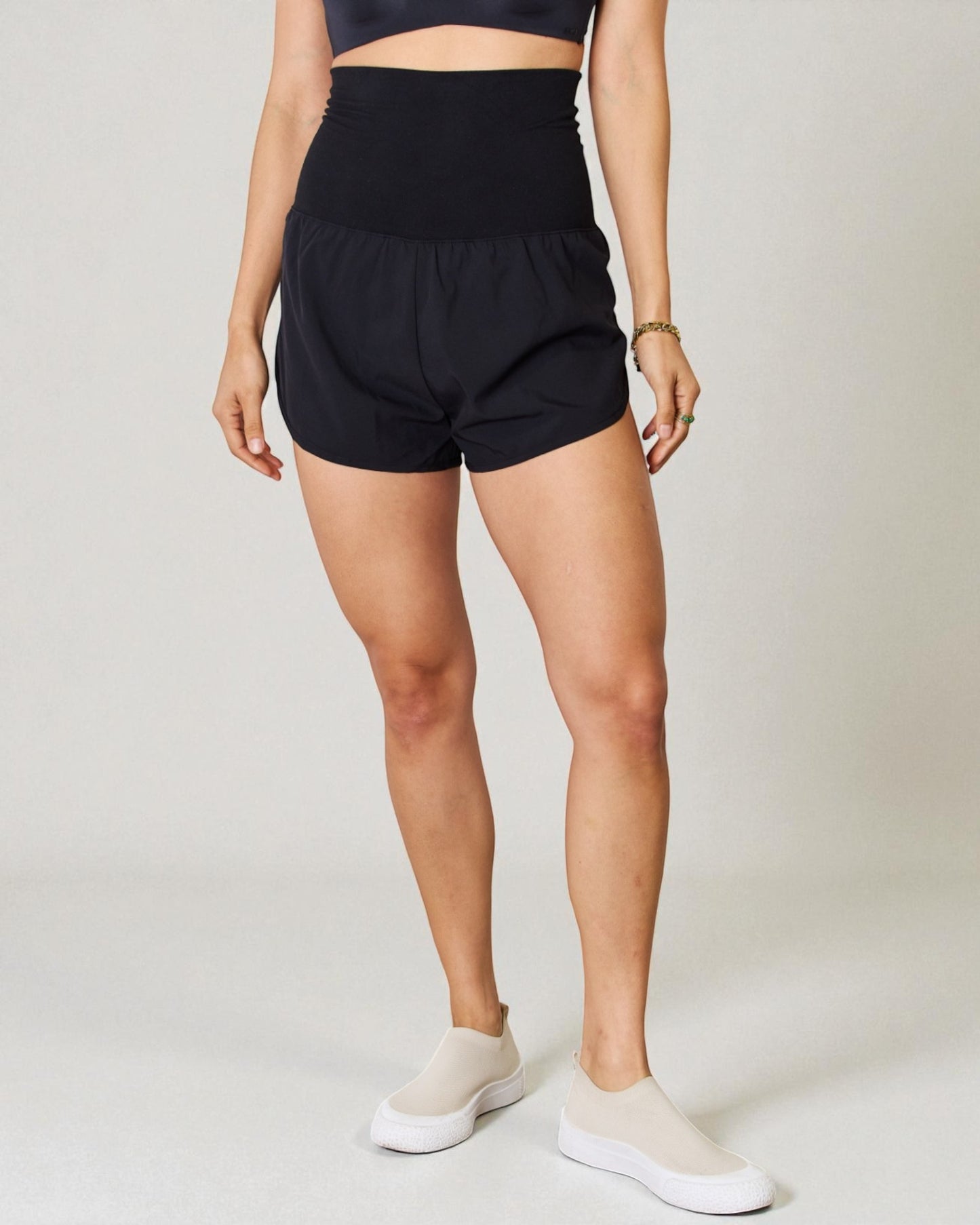 Person wearing black shorts on a plain background