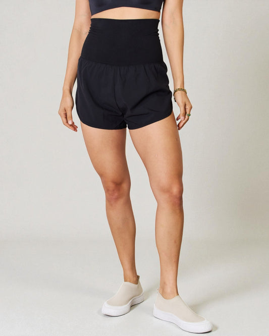 Person wearing black shorts on a plain background