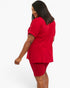 A woman modeling a bright red short-sleeve top and matching red biker shorts against a plain white studio background.