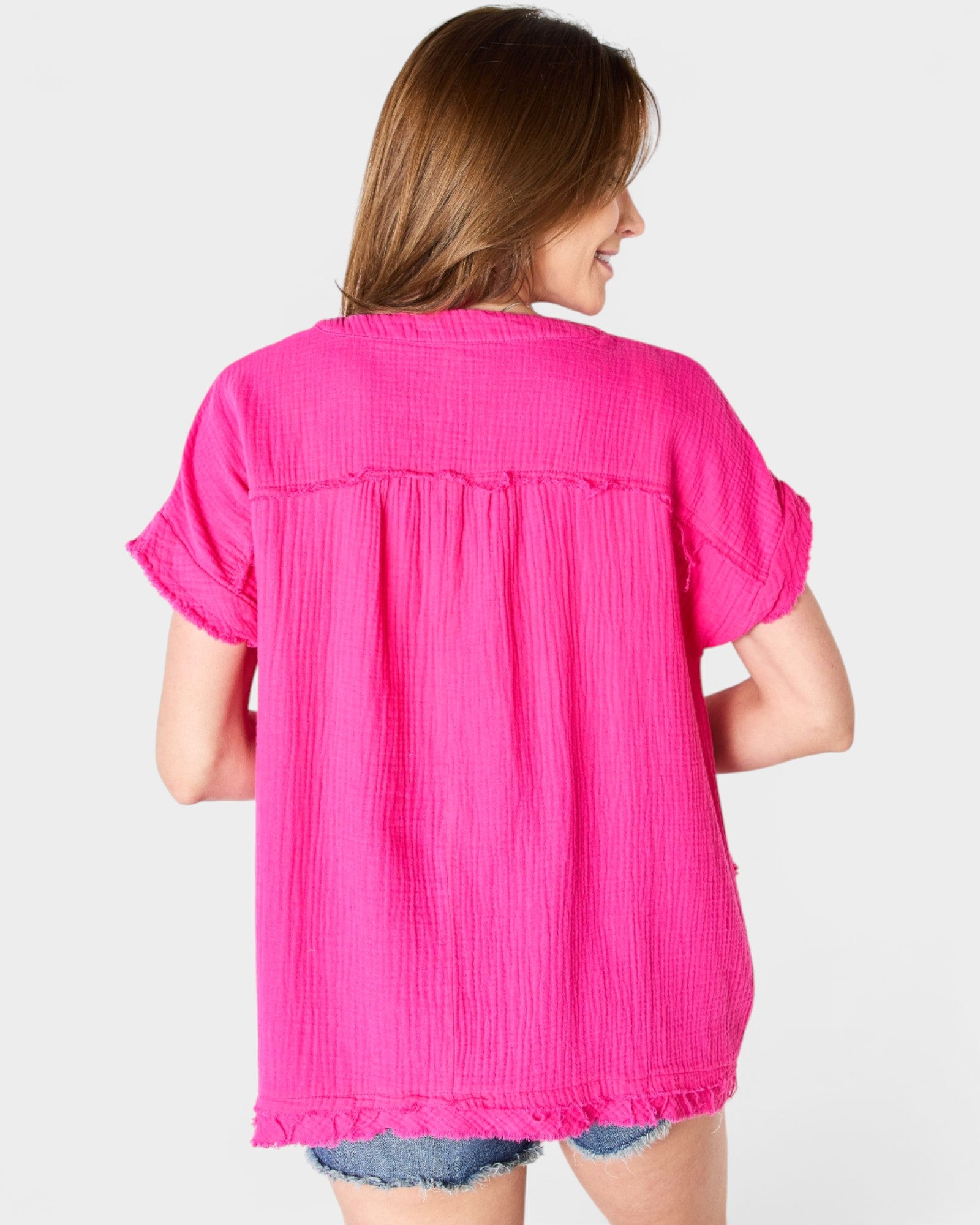 Woman wearing a bright pink blouse on a plain background