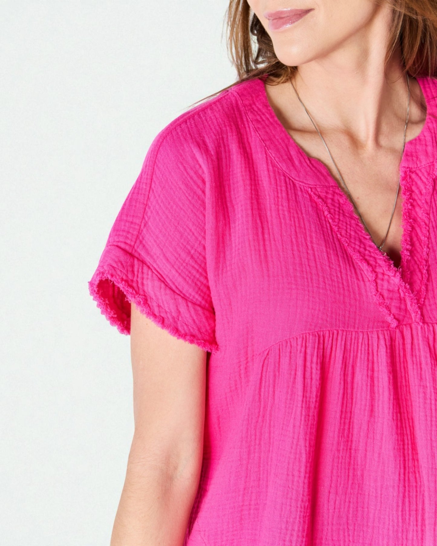 Close-up of a person wearing a bright pink top on a light gray background