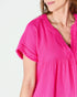 Close-up of a person wearing a bright pink top on a light gray background