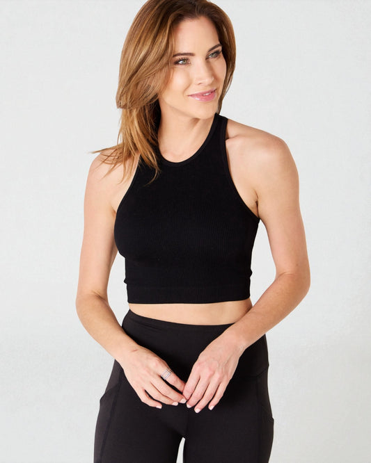 Woman wearing a black crop top and leggings on a light gray background