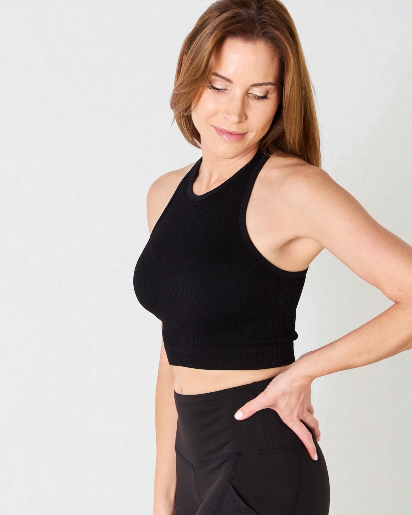 Woman wearing a black sports bra and leggings on a light gray background