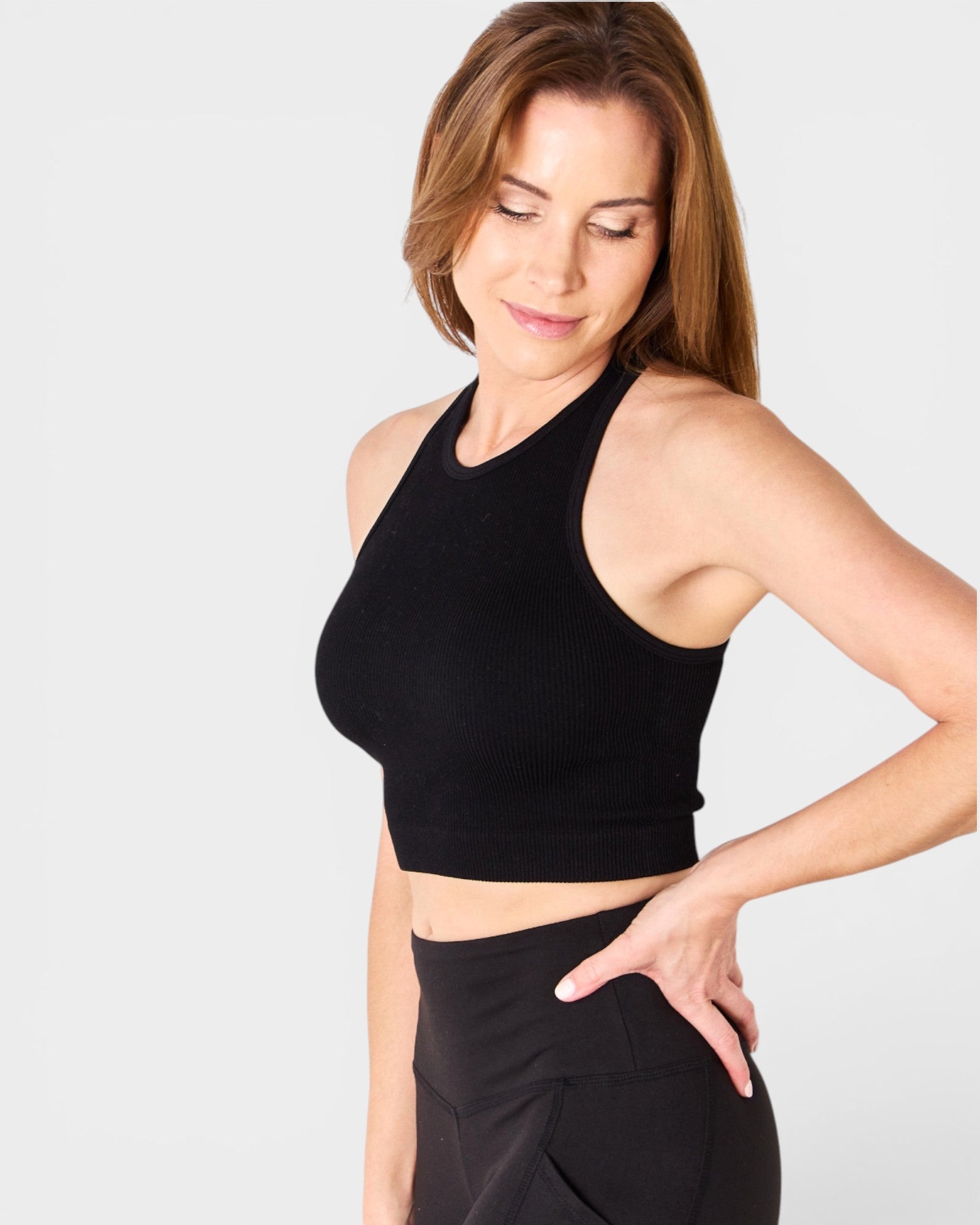 Woman wearing a black sports bra and leggings on a light gray background