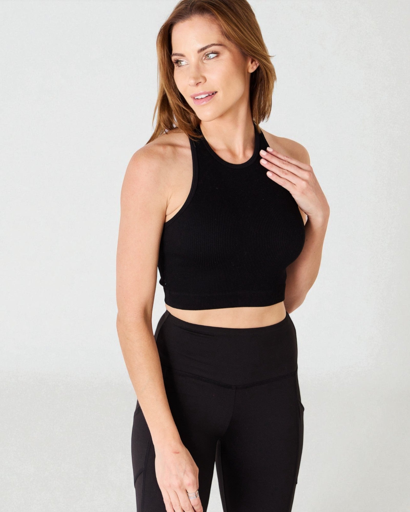 Woman wearing a black sports bra and leggings on a white background