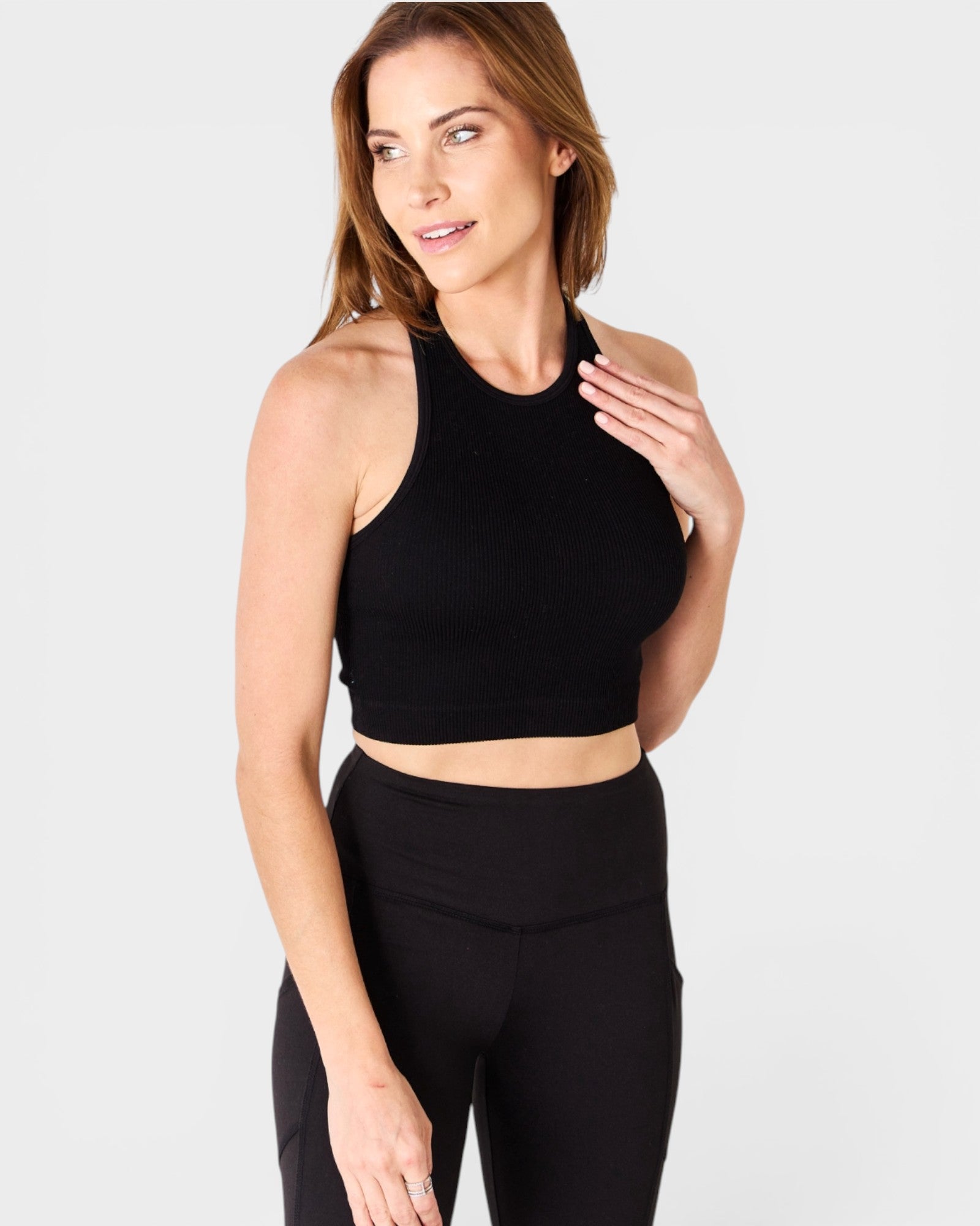 Woman wearing a black sports bra and leggings on a white background