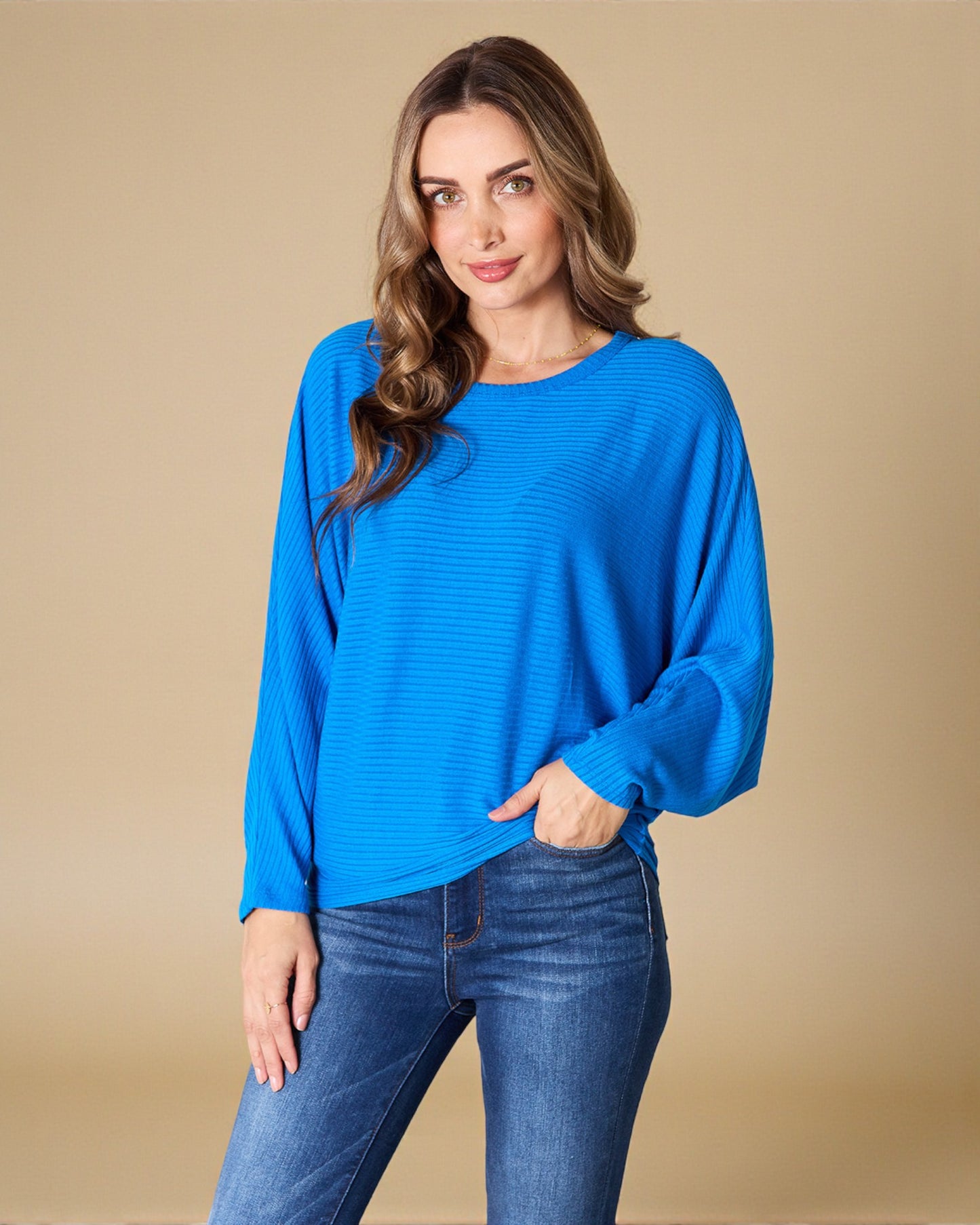 Woman wearing a blue sweater and jeans against a beige background