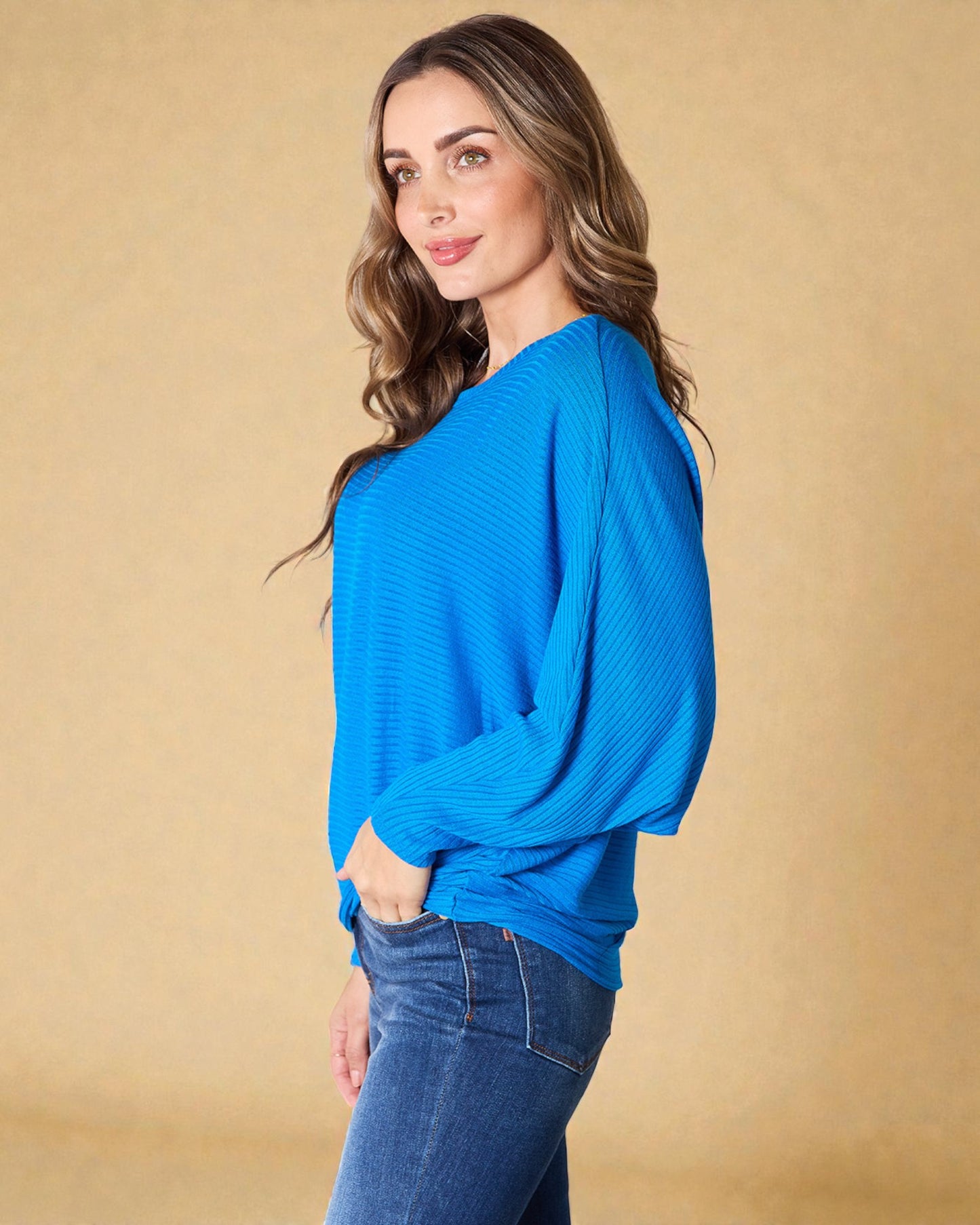 Woman wearing a blue sweater and jeans against a beige background