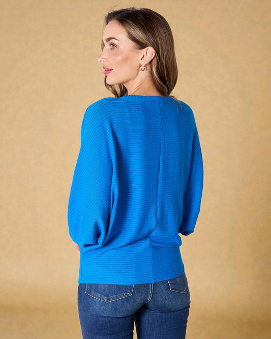 Woman wearing a blue sweater against a beige background