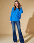 Woman wearing a blue sweater and jeans against a beige background
