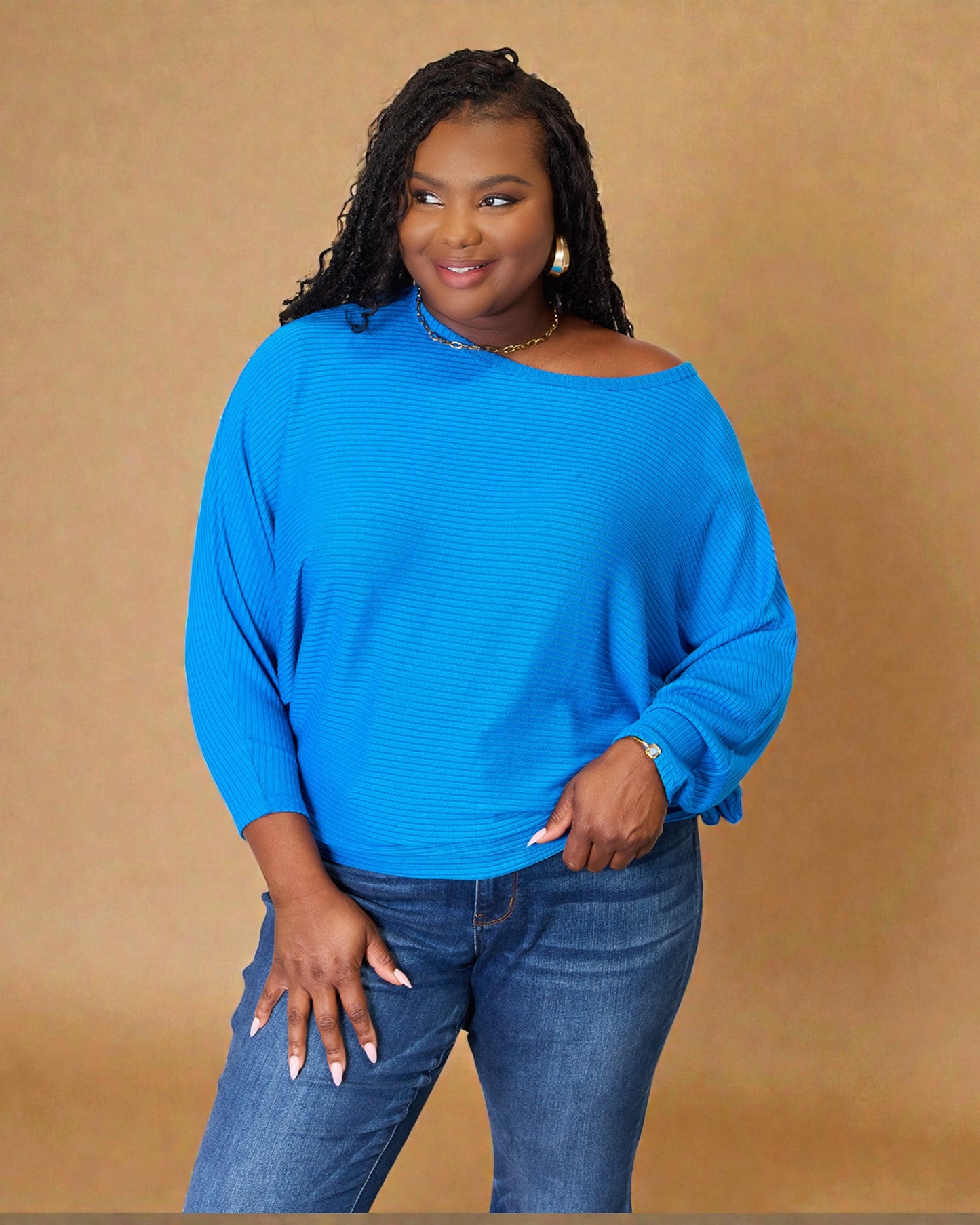 Woman wearing a blue sweater and jeans against a beige background