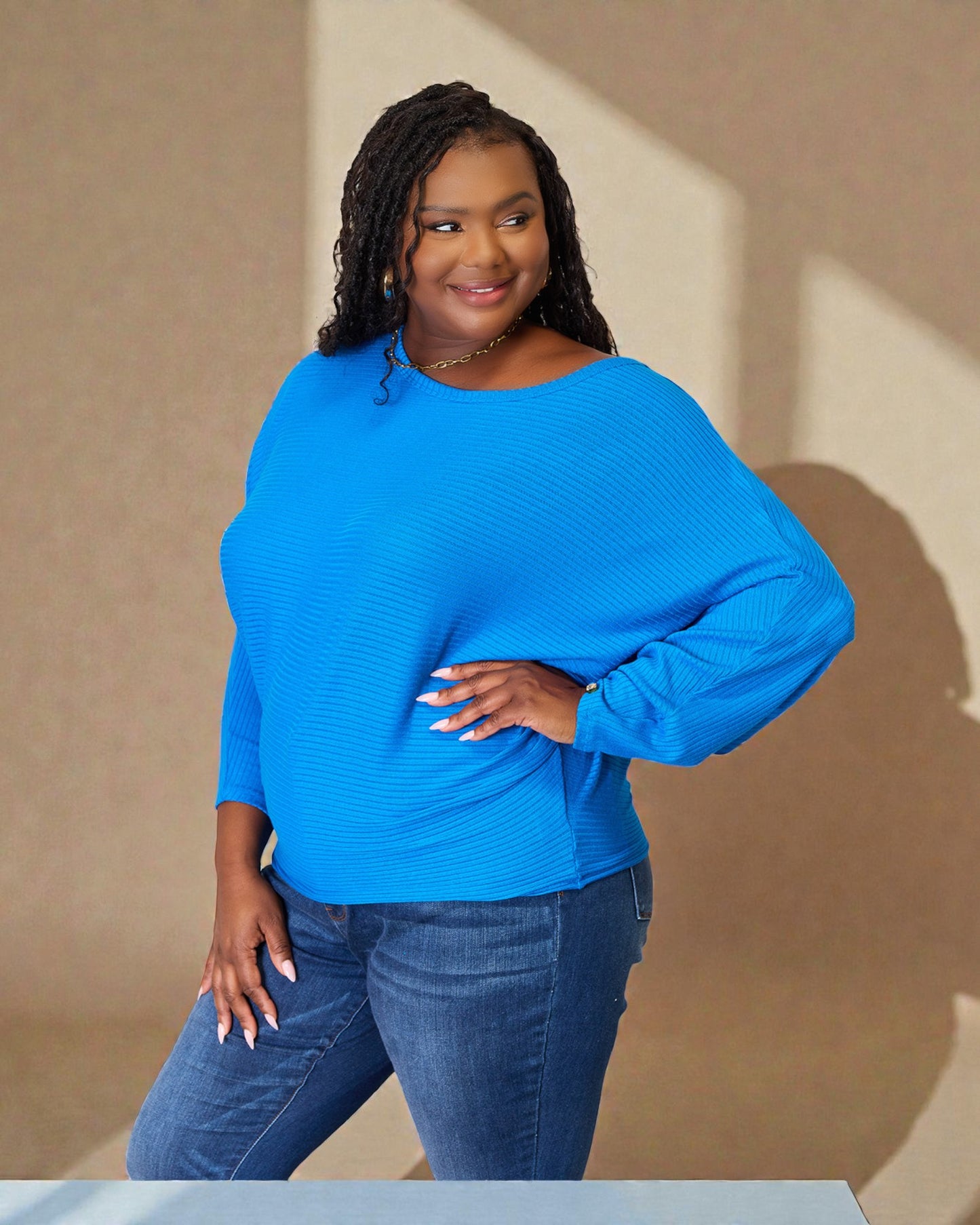 Woman wearing a blue sweater and jeans against a beige background