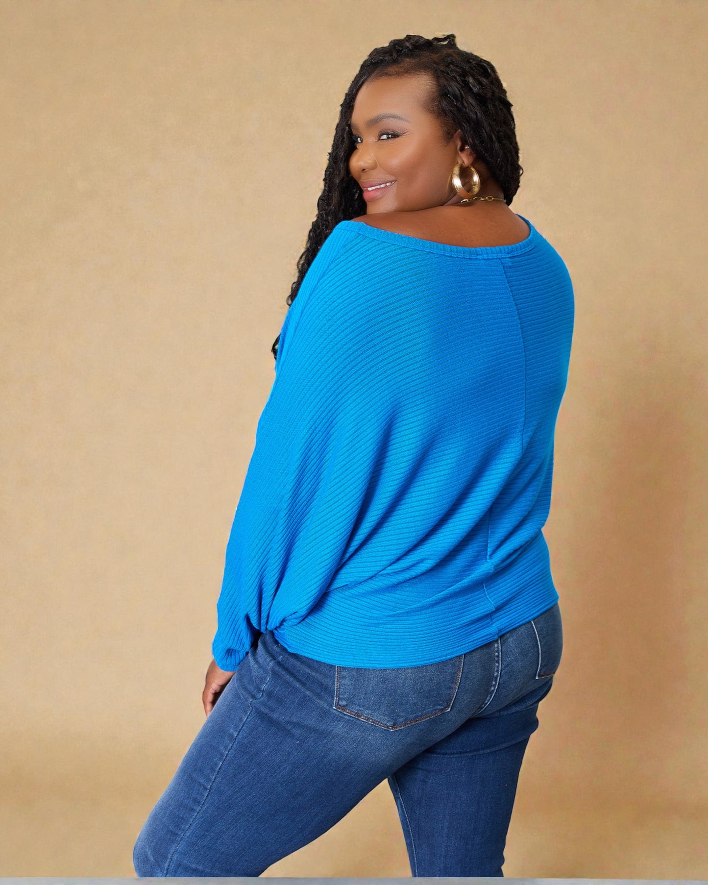 Woman wearing a blue sweater and jeans against a beige background