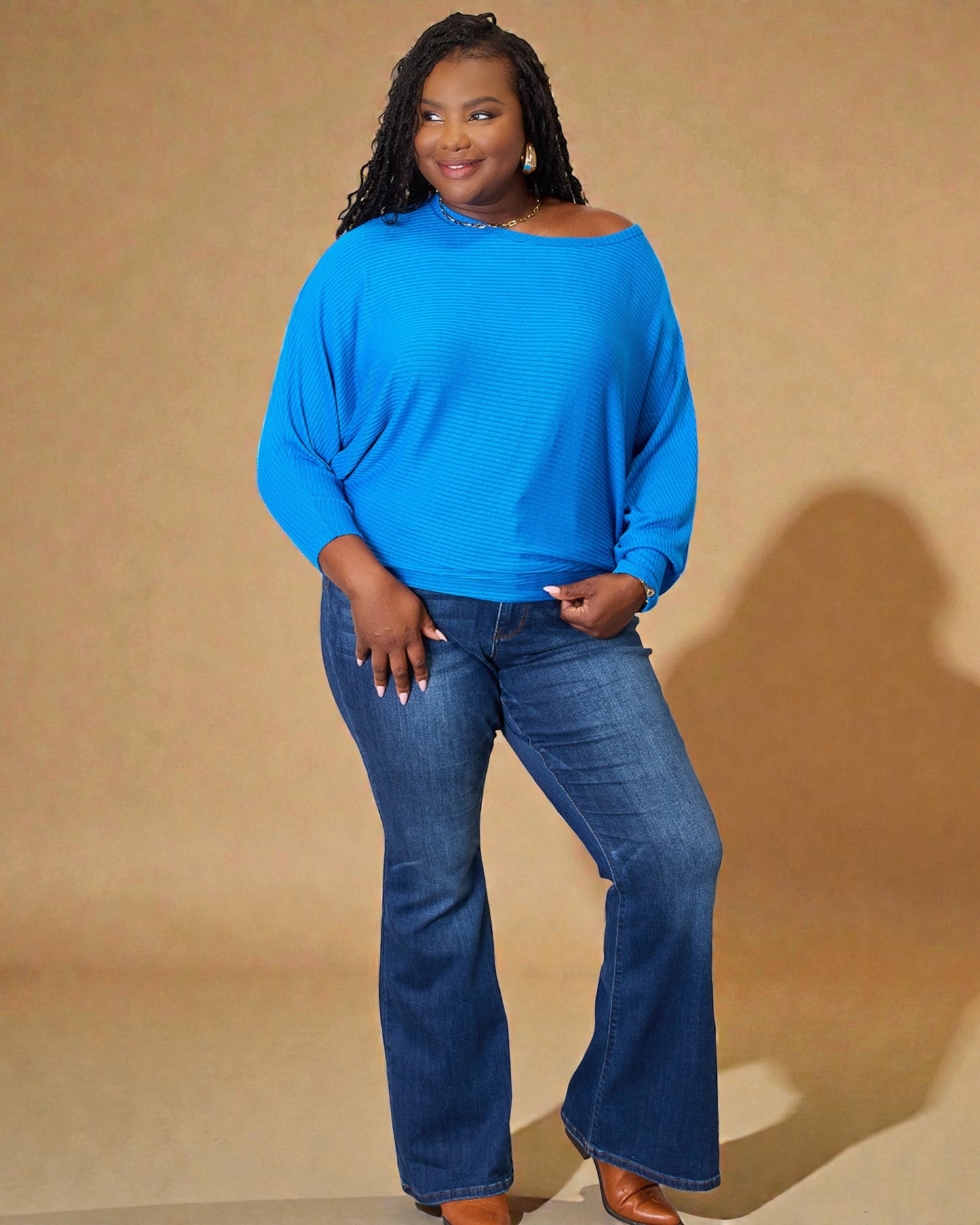 Woman wearing a blue sweater and jeans against a beige background