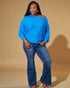 Woman wearing a blue sweater and jeans against a beige background