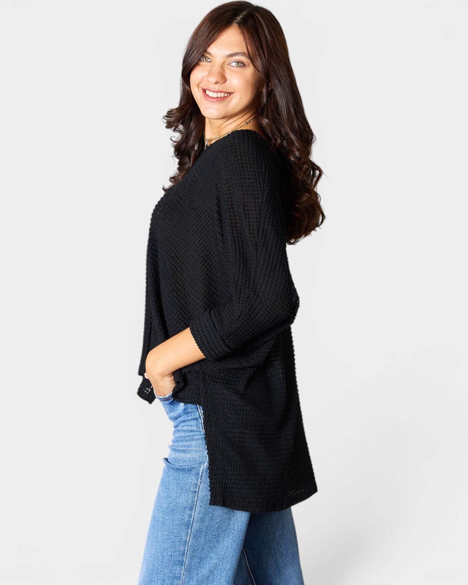 Woman wearing a black sweater and blue jeans on a white background