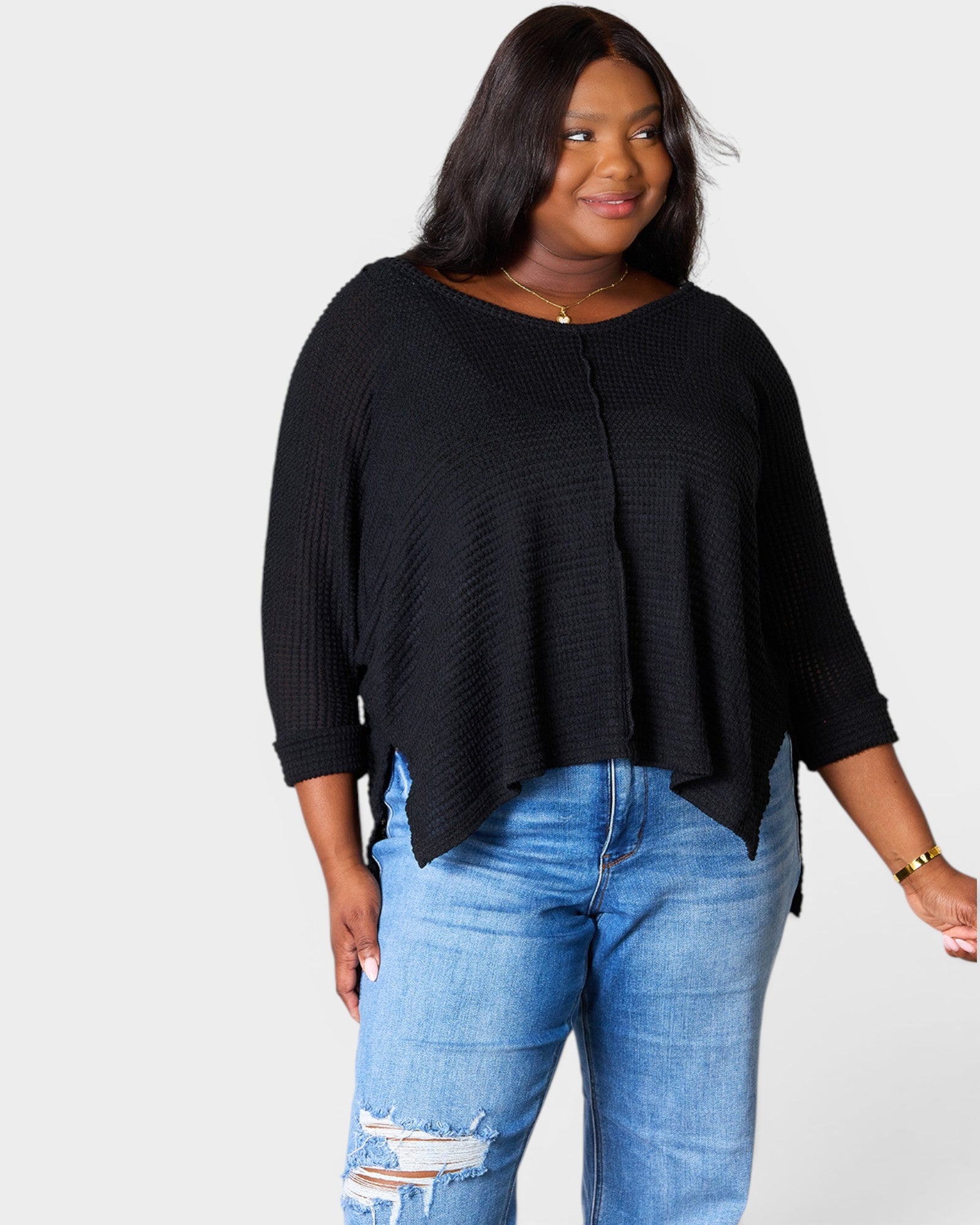 Woman wearing a black sweater and blue jeans on a white background