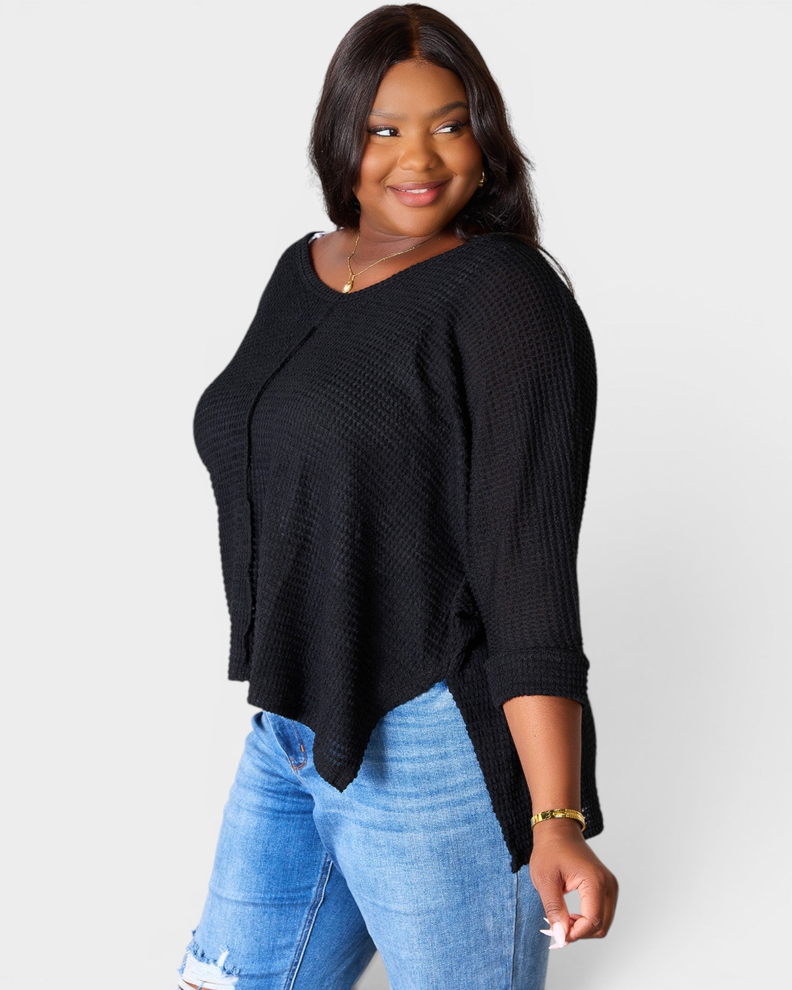 Woman wearing a black sweater and blue jeans on a white background