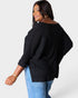 Woman wearing a black sweater and blue jeans on a white background
